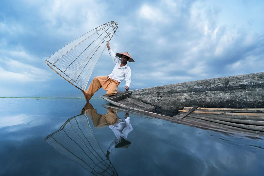 hinh anh nguoi dan ong cheo thuyen bang mot chan